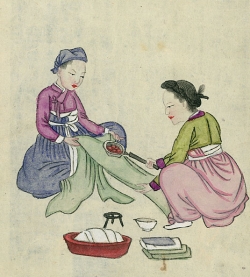 Two people using pan iron on length of fabric