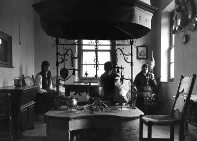 Kitchen with raised cooking hearth, wrought iron furnishings, masonry hood