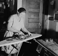 Woman using sad iron on folding ironing board