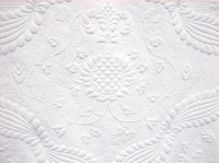 section of white quilt with raised floral design